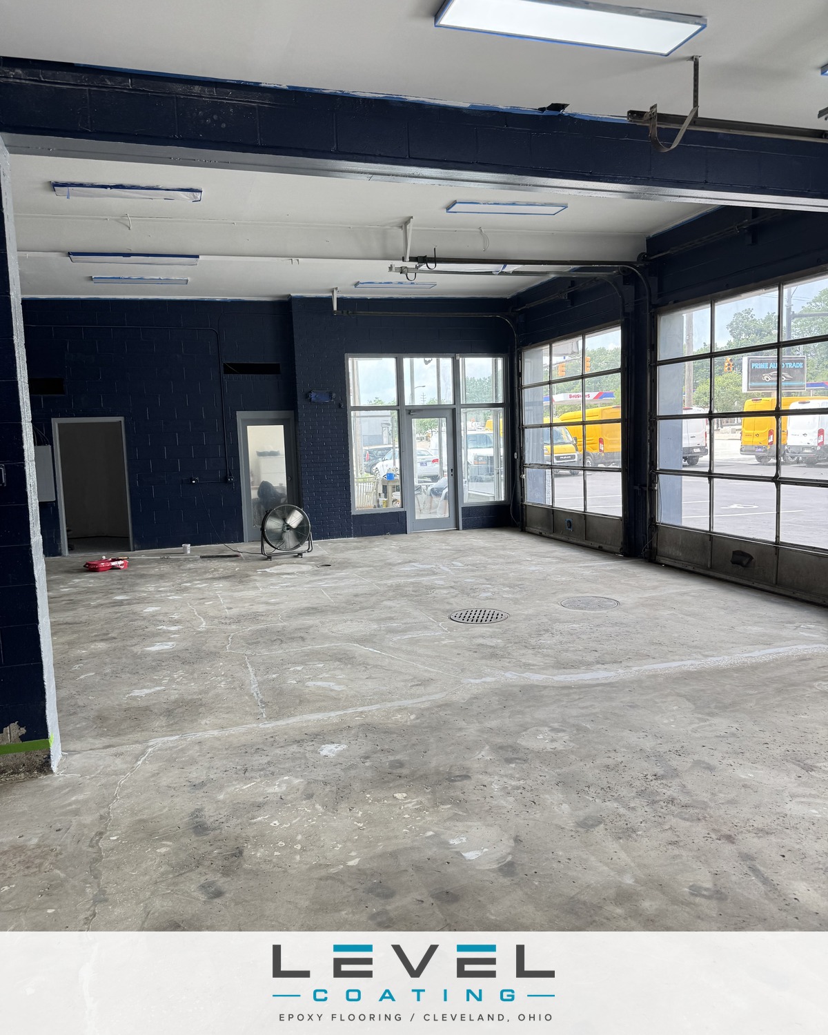 Bare stained concrete in a dealership service bay before coating - Akron, OH