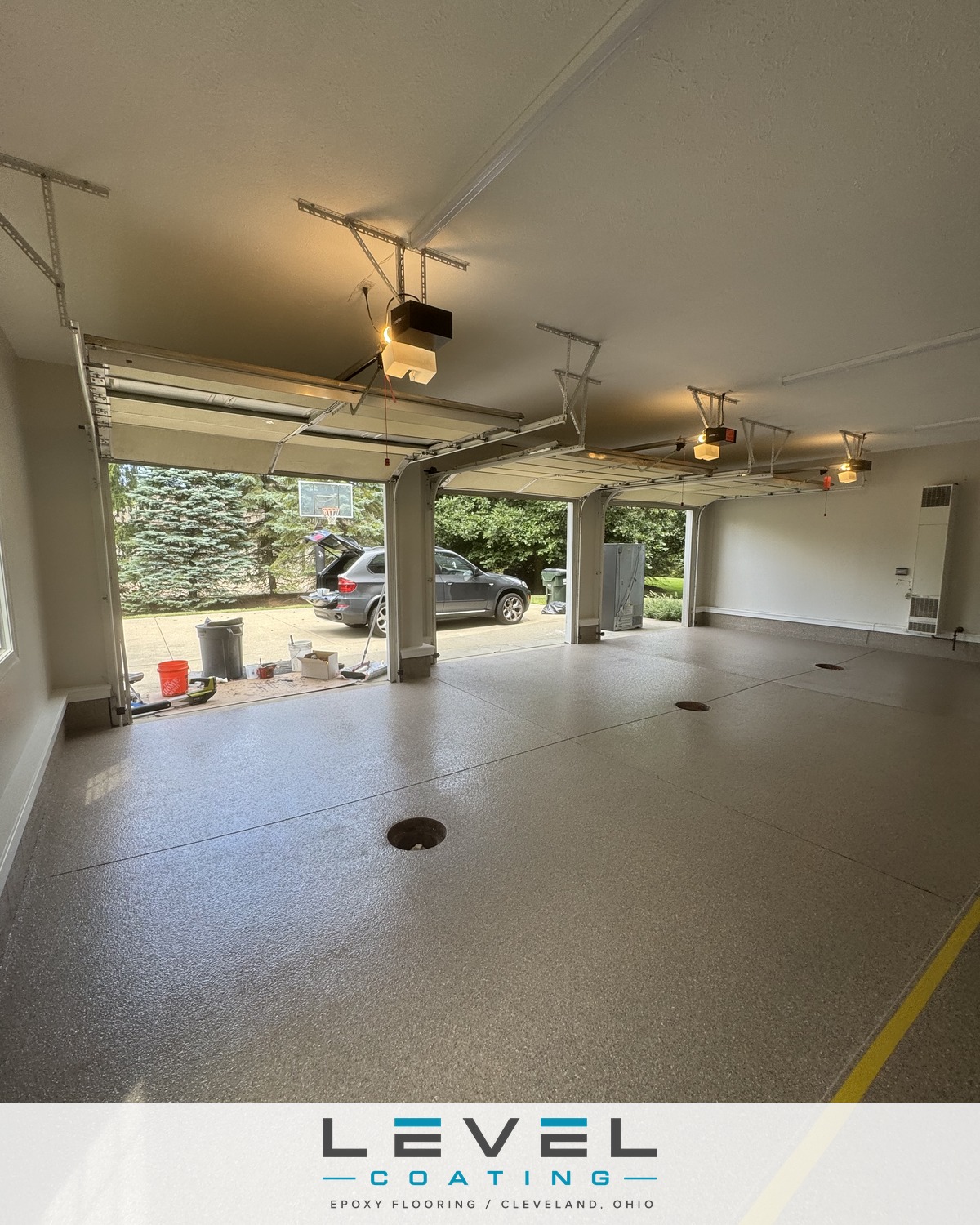 Three-car garage after a Level Coating polyaspartic floor with safety marker line - Solon, OH